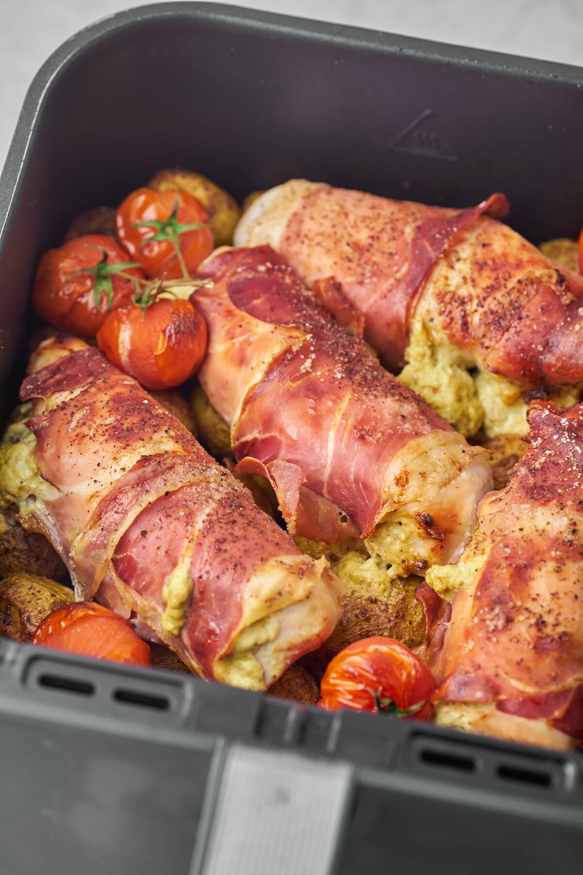 air fryer basted with filled chicken breast, potatoes and tomatoes
