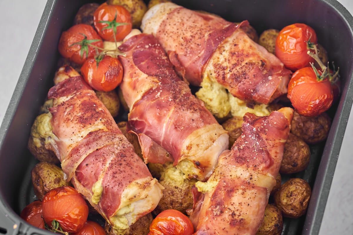 air fryer stuffed chicken breast with potatoes and tomatoes in air fryer basket