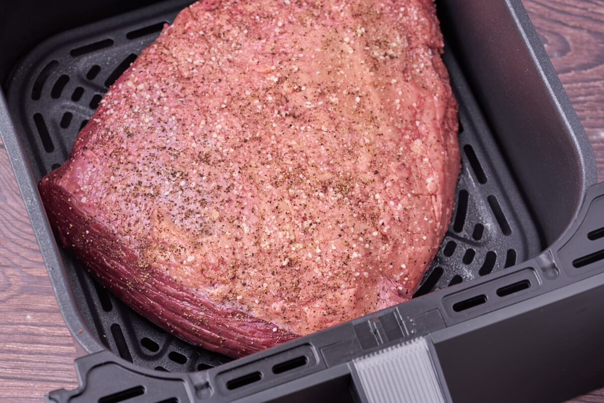 air fryer basket with raw rump cap before cooking