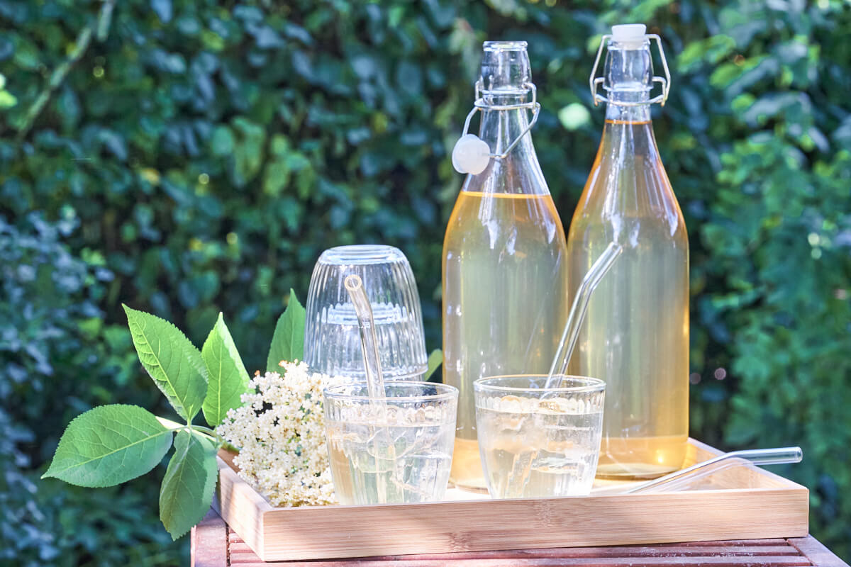 bottles with elderflower cordial and two glasses with drinks