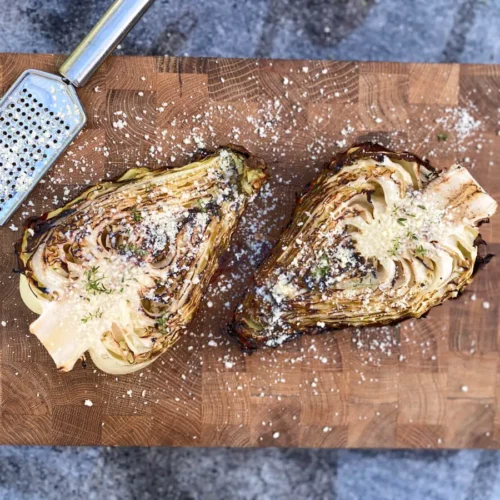 grilled pointed cabbage with parmesan and thyme on wooden cutting board