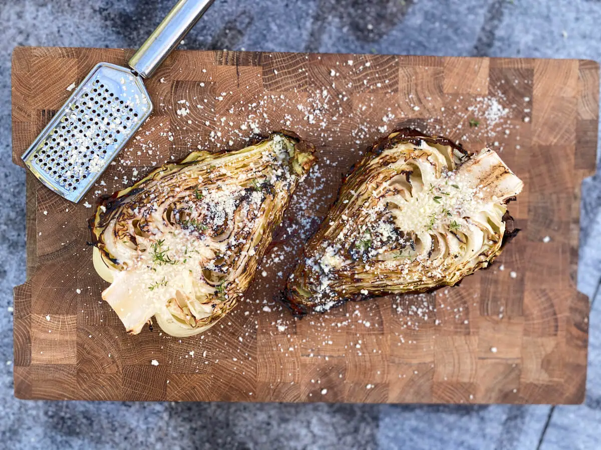 grilled pointed cabbage with parmesan and thyme on wooden cutting board