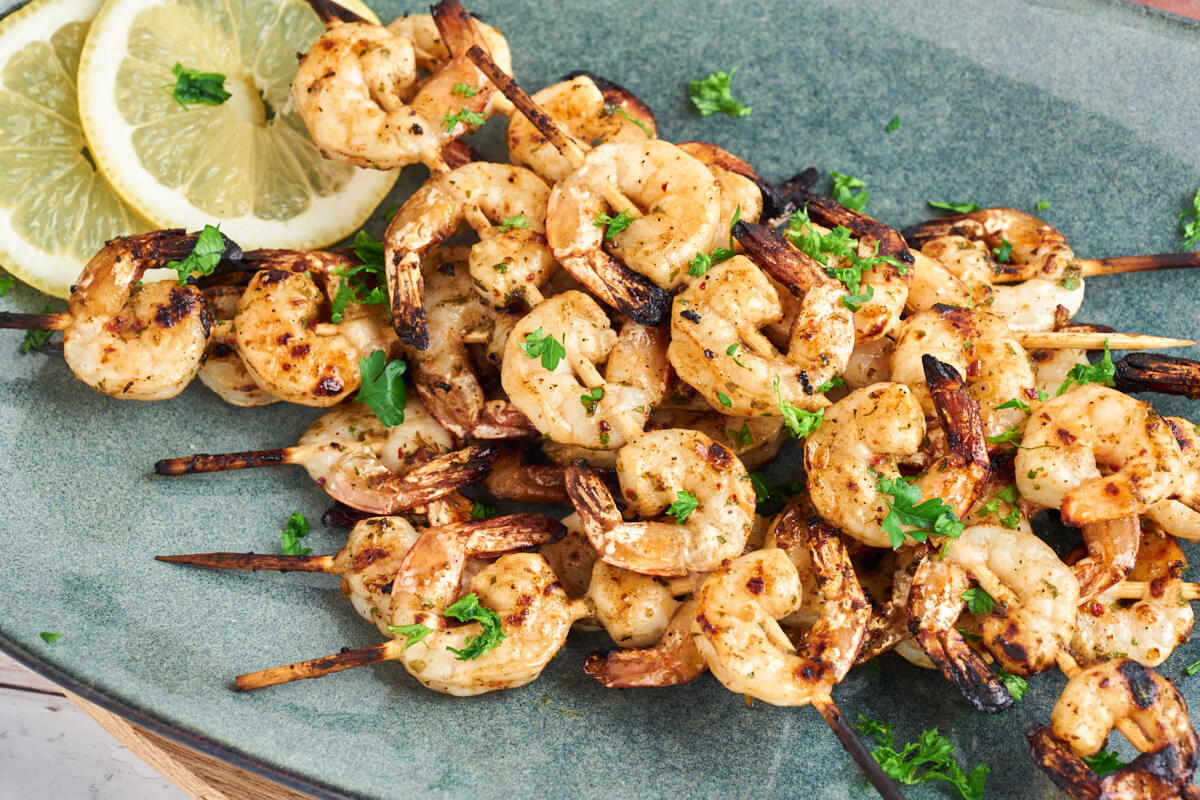 marinated grilled shrimp skewers on plate with lemon slices