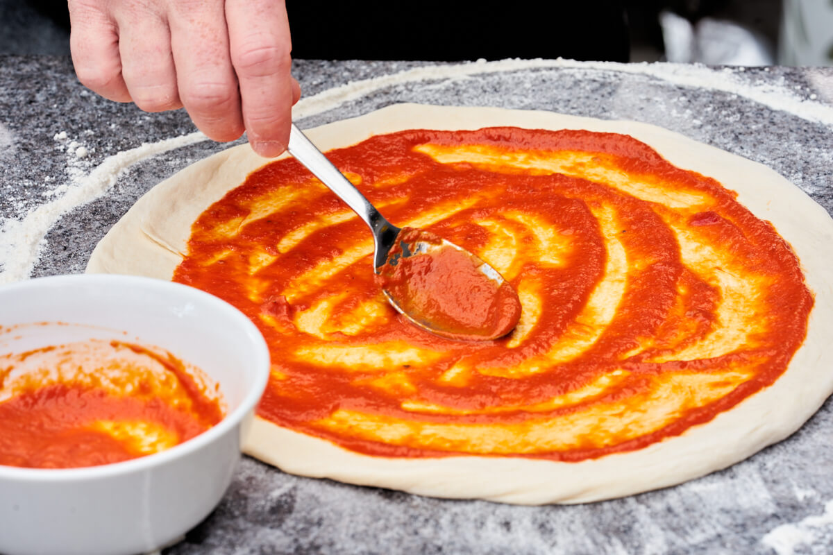 pizza dough covered in pizza sauce