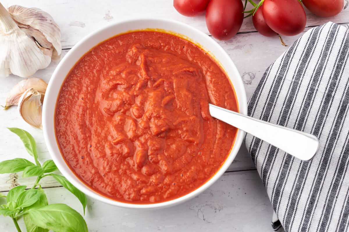 homemade pizza sauce with tomatoes, garlic and bazil in bowl