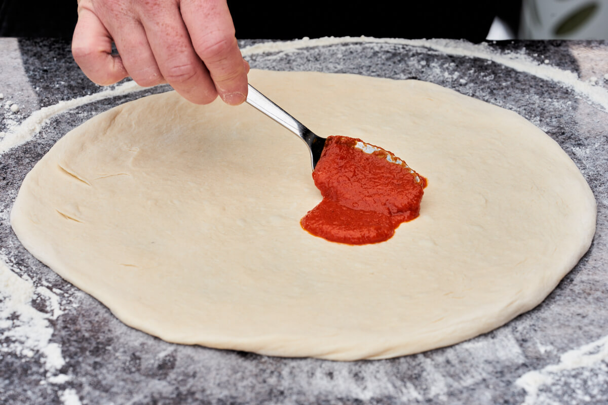 pizza dough and spoon with sauce