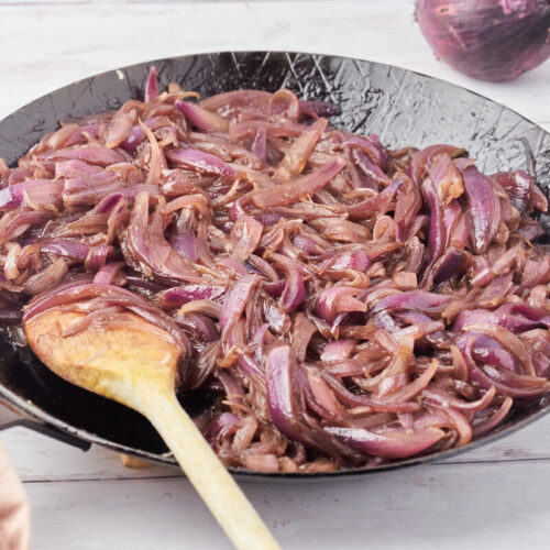 caramelized onions in frying pan with wooden spoon