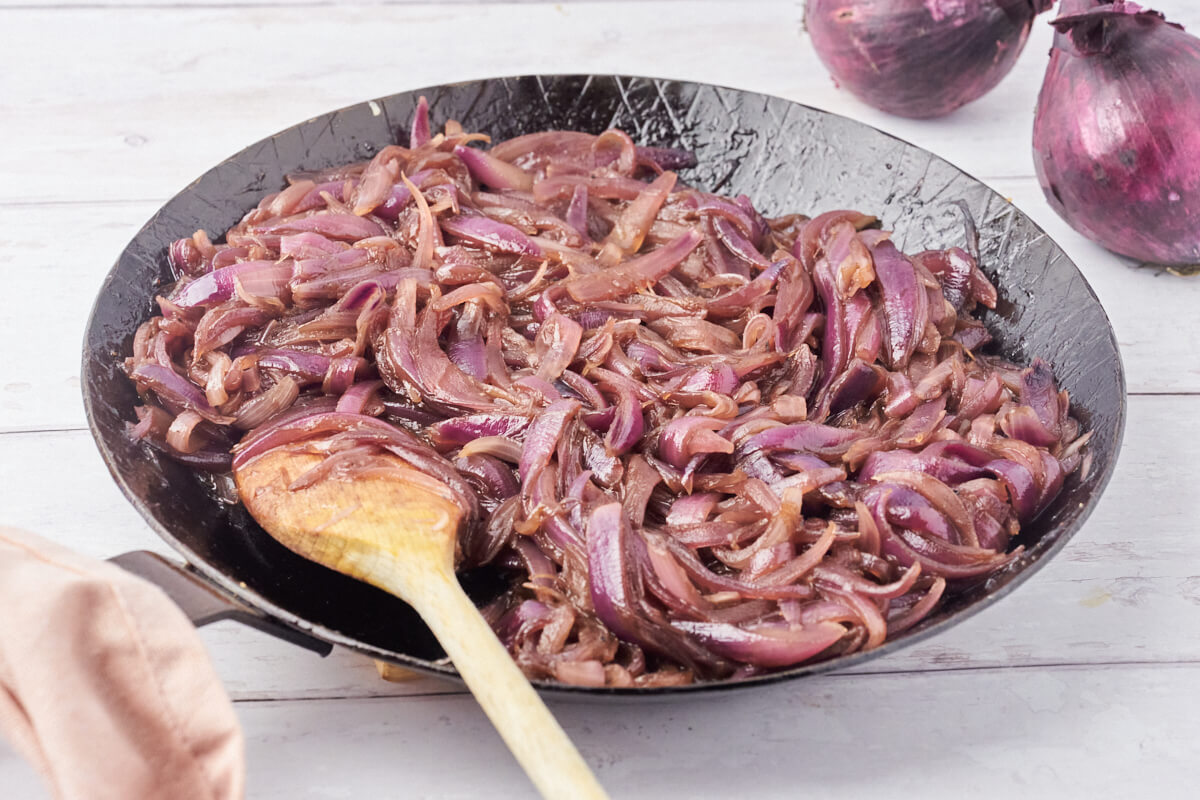 caramelized onions in frying pan with wooden spoon