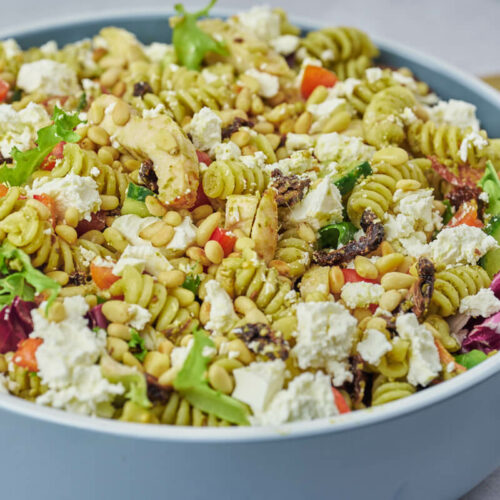 chicken pesto pasta salad with sun-dried tomatoes, feta cheese and pine nuts in bowl