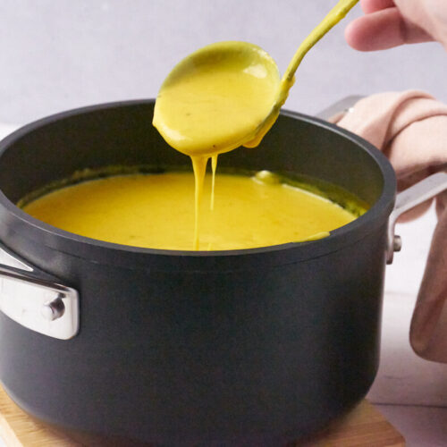 danish curry sauce in small black pot with spoon