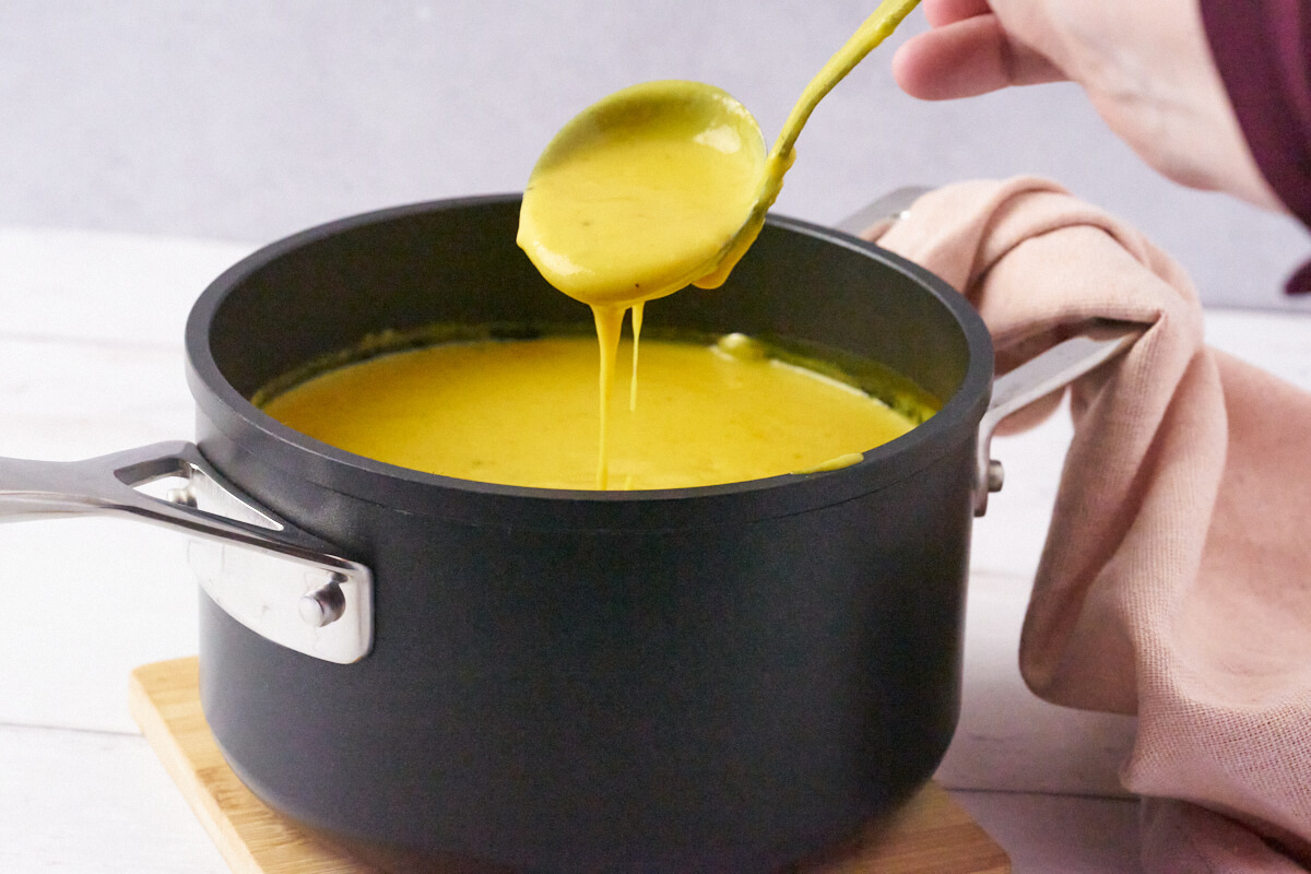 danish curry sauce in small black pot with spoon