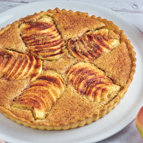 frangipane apple tart on plate with fresh apples and knife