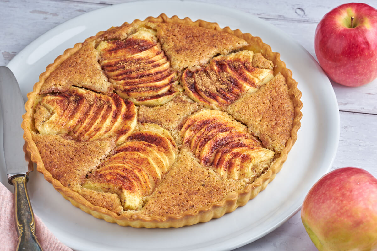 frangipane apple tart on plate with fresh apples and knife