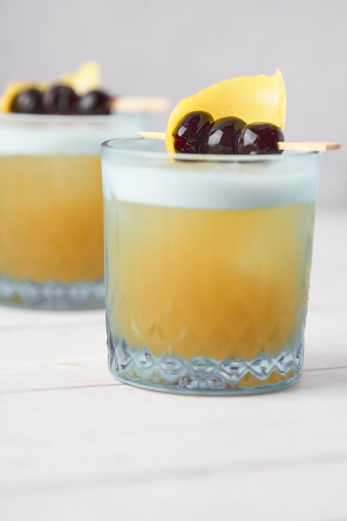 Glasses with classic Amaretto Sour with lemon and cherries on top