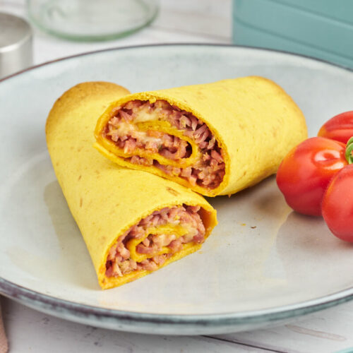 Pizza roll ups in tortillas ready for the lunchbox along with tomatoes