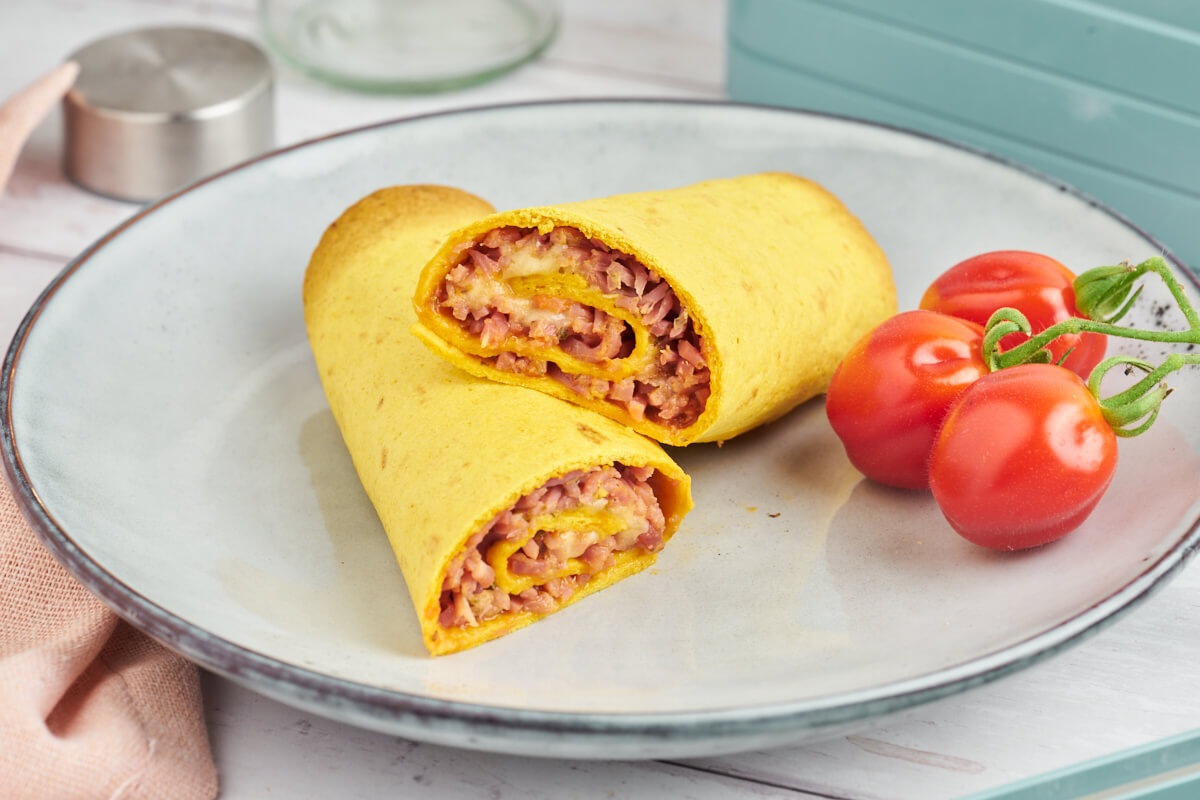 Pizza roll ups in tortillas ready for the lunchbox along with tomatoes