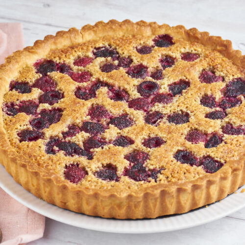 raspberry frangipane tart on a plate with a knife