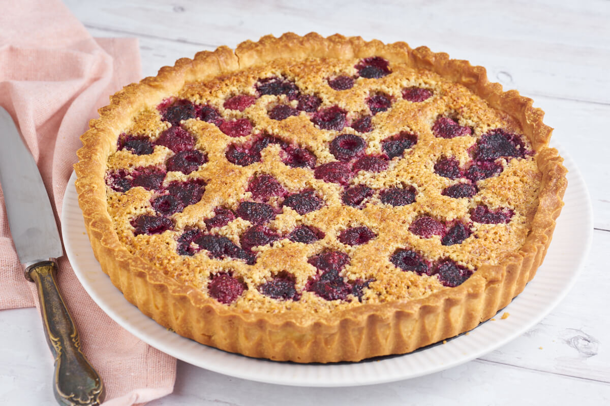 raspberry frangipane tart on a plate with a knife