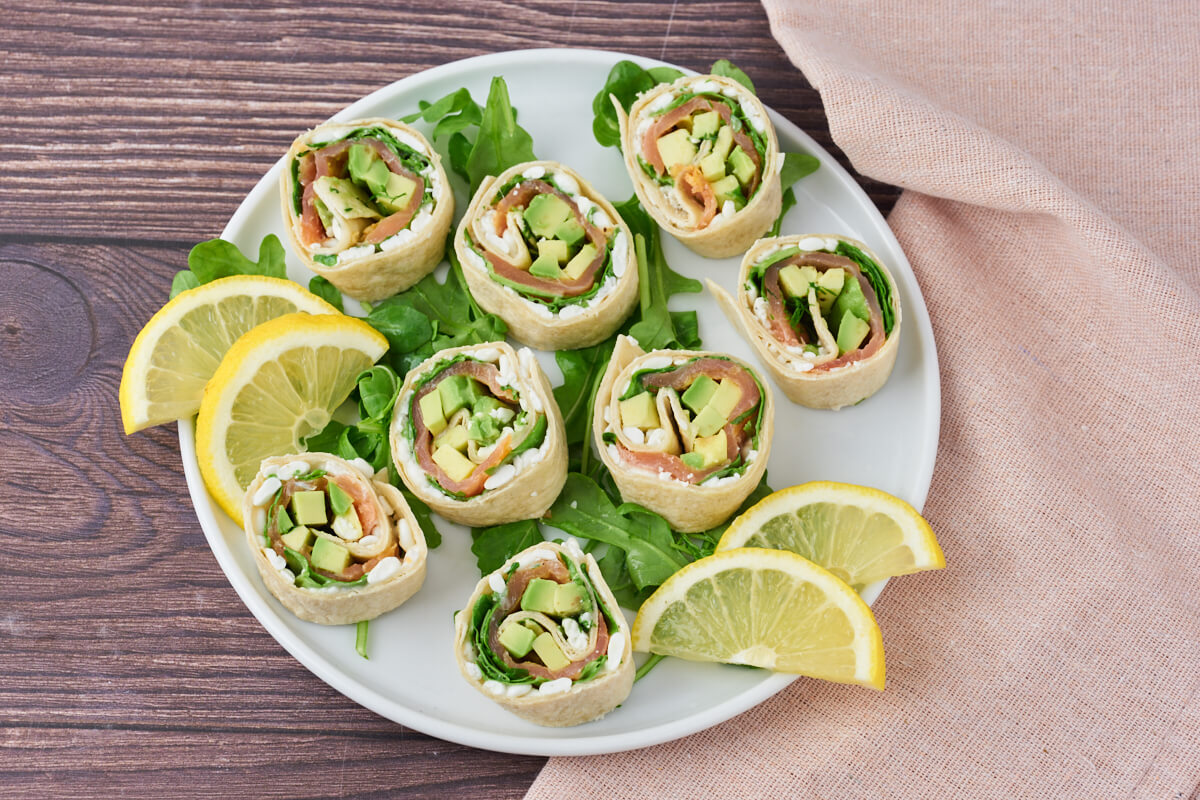 Salmon wraps with cottage cheese and avocado on a platter with salad and lemon