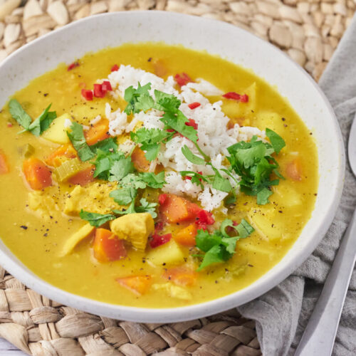 servering of the mulligatawny soup in a bowl with rice, chili and cilantro