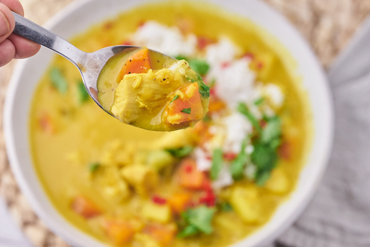 a spoonful of mulligatawny with carrots, celery end chicken in the creamy soup