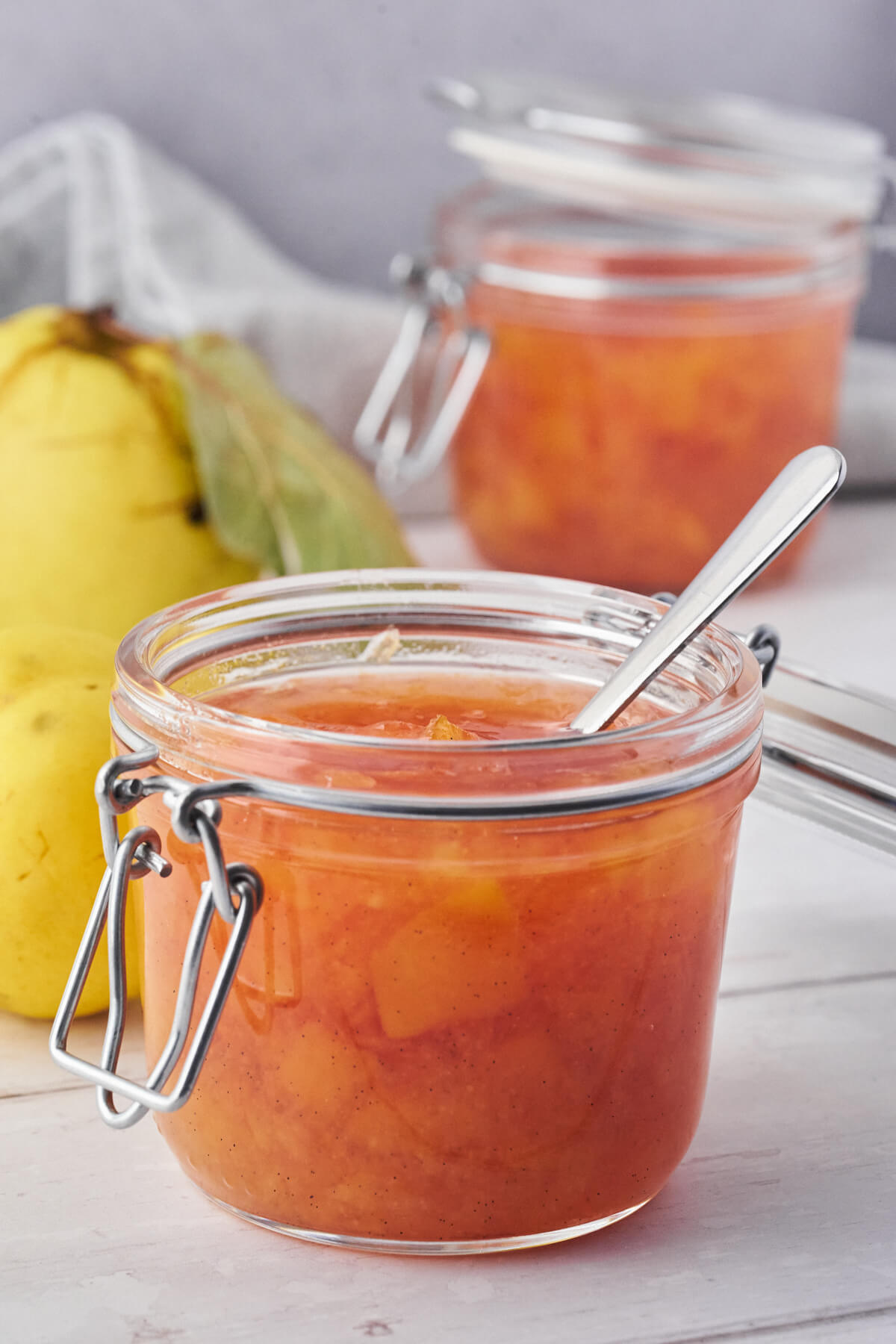 quince jam in a jar with a spoon and quinces