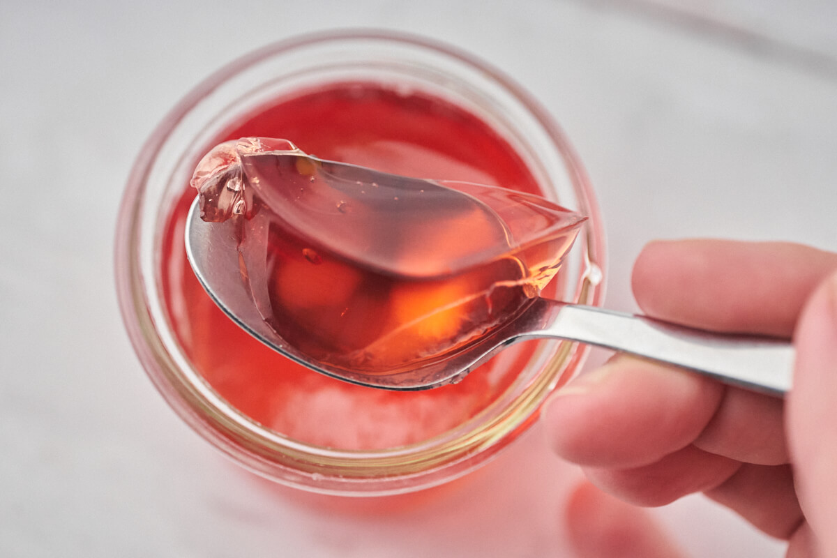 Small jar of quince jelly with a spoon and a spoonful of jelly on top