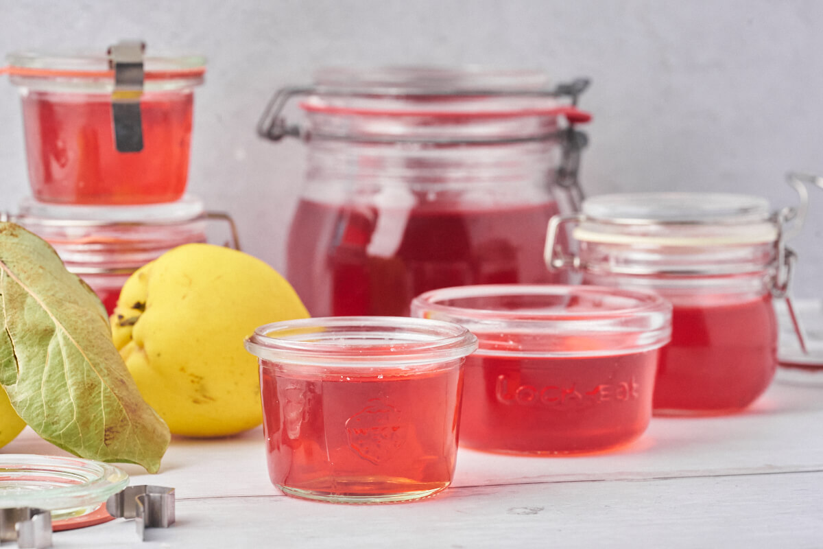 Red quince jelly in a jar with fresh quinces beside it