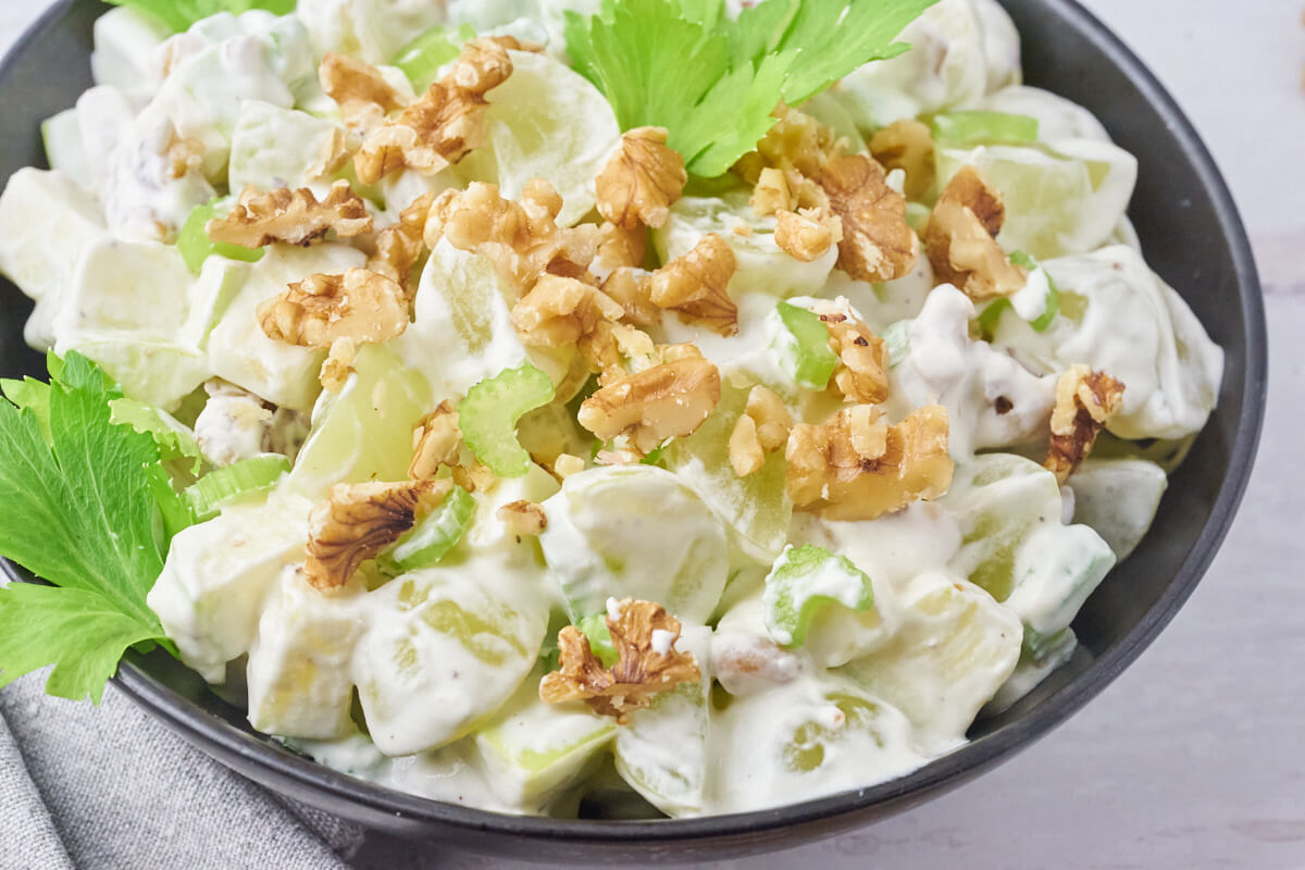 Garnishing Waldorf salad with walnut kernels and celery leaves.