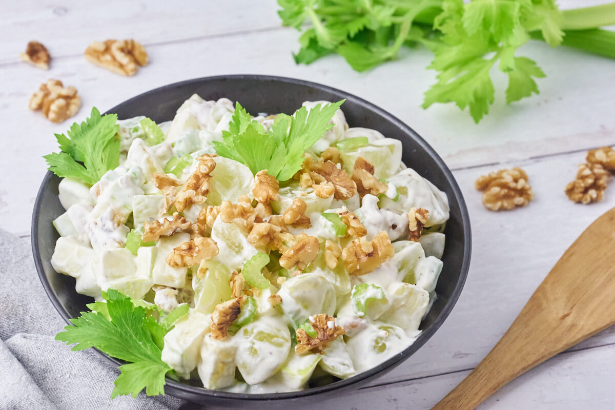 Old-fashioned Danish Waldorf salad in a bowl with salad serving utensils.