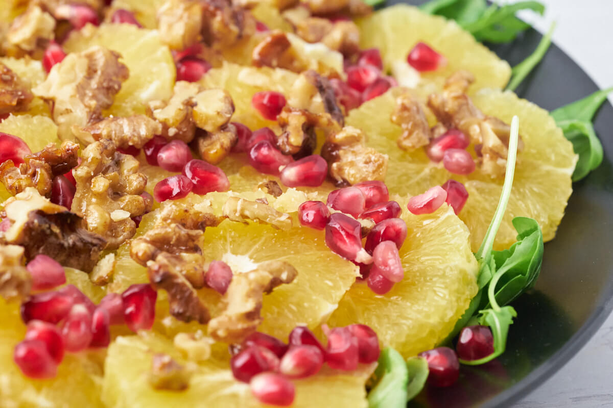 Arugula with slices of orange, pomegranate seeds, and honey-roasted walnuts.